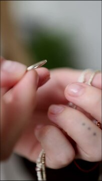 macro of female hands holding jewelry. necklace with red thread in the shape of Morse code. vertical video