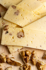 Sliced piece of milk cheese with walnuts