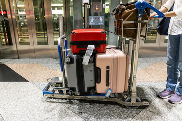 Traveller pushing trolley with luggages and bags in airport terminal