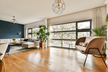 a living room with blue walls and hardwood flooring, white sofas and two chairs in front of the window