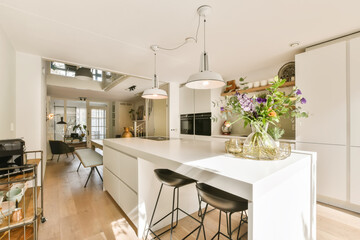 a kitchen and dining area in a house with white walls, hardwood flooring and an open plan to the living room