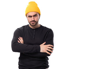 brutal handsome young 30 year old guy dressed in a black jacket and a yellow hat on a white background with copy space