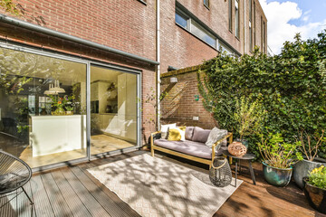 an outdoor living area with wooden decking and glass doors leading out onto the terraced back yard,...