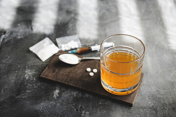 Alcohol drink in a glass, syringe with a dose of drugs, white pills and narcotics powder in a...