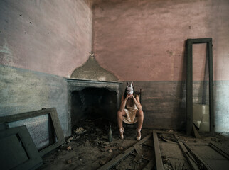 girl with rabbit mask, next to a fireplace in an abandoned house