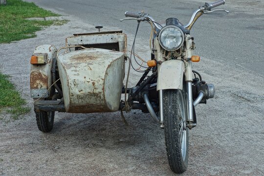 old retro iron made in the ussr heavy powerful with a sidecar and a gray spare tire a motorcycle stands in the road  on the street during the day
