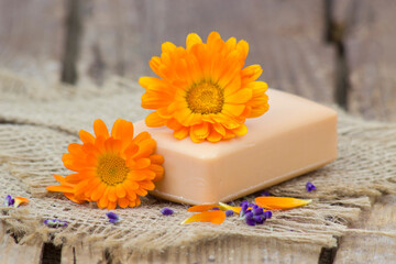 Natural handmade soap with calendula (pot marigold) on rustic wooden background - obrazy, fototapety, plakaty