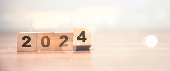 Flipping of 2023 to 2024 on wooden block cube with bokeh for preparation new year change and start...