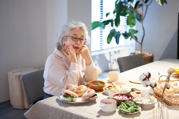 さみしそうな表情で食事をするシニア女性