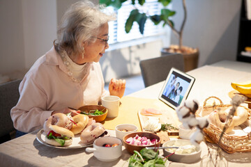 食事をしながら孫たちとのテレビ電話を楽しむおばあさん
