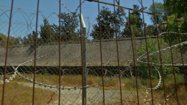 The camera is panning back and forth behind barbed wires over a 'UN' buffer zone. Nicosia, Cyprus.