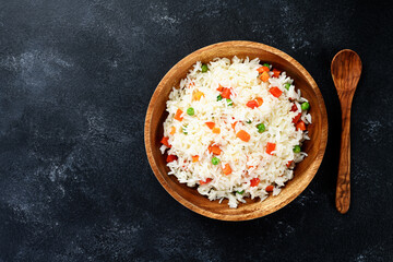 Wooden plate with vegetable fried rice - healthy vegetarian food. Dark background . top view