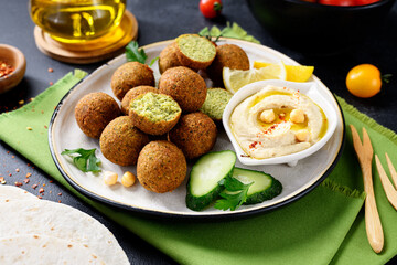 Plate of chickpeas falafel balls with hummus, vegetables  and lemon slices.