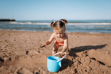 little child sea, girl in swimsuit joyful plays on the beach