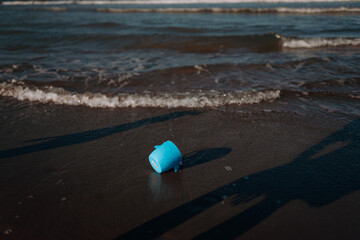 Fototapeta na wymiar children's plastic bucket on the sand near the water