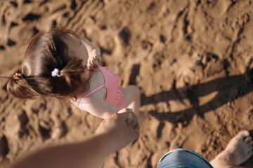 little child sea, girl in swimsuit joyful plays on the beach