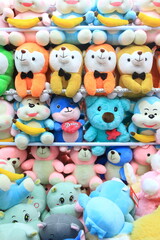 Fototapeta na wymiar Row of colorful stuffed animal dolls inside claw crane game.