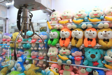 Close up of mechanical claw to pick up dolls in claw crane machine game. - obrazy, fototapety, plakaty
