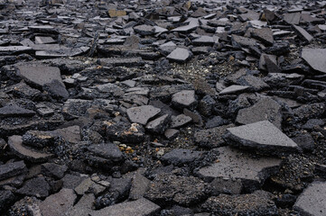 Area of black tarmac which has been broken up by severe trauma