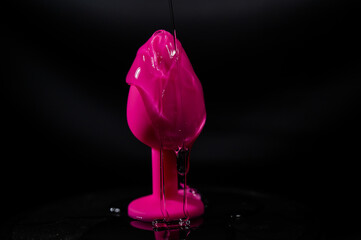 Pink anal plug in intimate lubricant on a black background. 