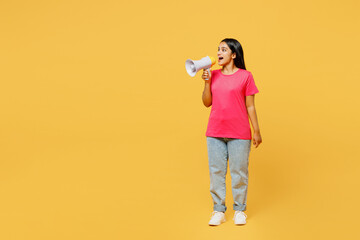 Full body young Indian woman wearing pink t-shirt casual clothes hold in hand megaphone scream announces discounts sale Hurry up isolated on plain yellow background studio portrait. Lifestyle concept.