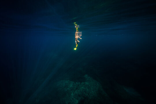 Anonymous man diving in deep blue ocean