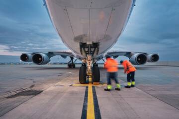 Low angle view of freight airplane. Ground staff at airport. Preparation cargo plane before flight during sunny day..