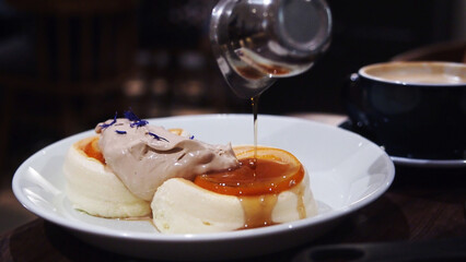 Fluffy Japanese souffle pancakes with cream on a white plate set on a wooden table