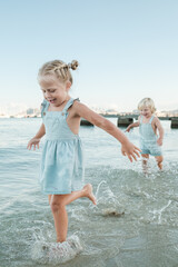 Cheerful cute children running in sea on coast in summer