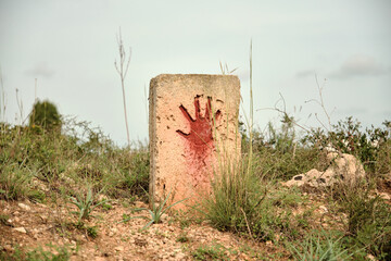 Red painted hand print on old stone in countryside