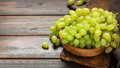 Bunch of green ripe grapes in a wooden bowl, on rustic wood background