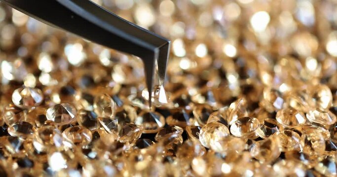 Jeweler holding expensive shiny diamond with tweezers closeup 4k movie slow motion. Making expensive jewelry concept