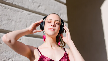 Smiling relaxed woman listening to music with headphones and breathing fresh air