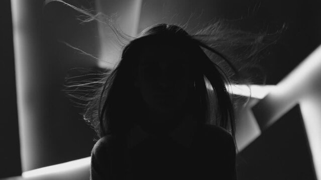 Close up portrait of pretty brunette female model . Beautiful attractive face of young woman . Hair flowing or blowing in wind . Face Changes Depending on the Lighting . Shadow and light movement . 