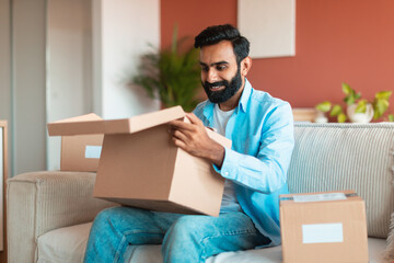 Happy Middle Eastern customer man opening cardboard boxes at home