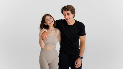Laughing cheerful young caucasian man hugging woman in sportswear enjoy workout together, have fun