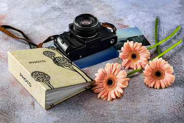Composition with an old camera, a photo album, color photos and pink gerbera flowers. World Photography Day, August 19, concept