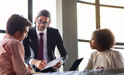 Handsome middle aged leader giving assignments to multiracial team employees