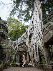 Girl watching tree roots invade angkor wat