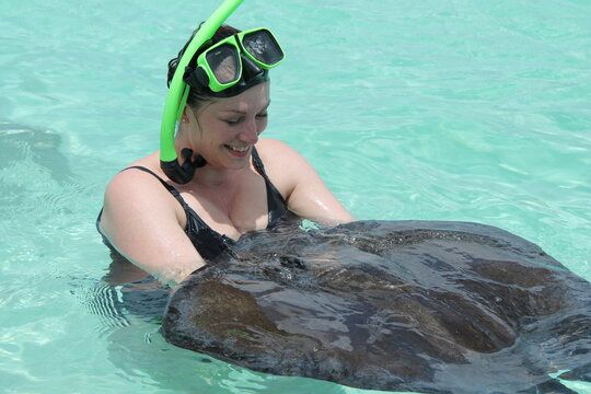 woman in water with sting ray on beach in Dominica, ray in womans arms