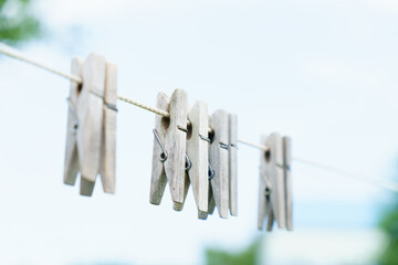 Old wooden clothespins hanging on a rope.