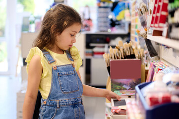 Adorable child girl, choosing school stationery in office supply store. Back to school on new semester of academic year