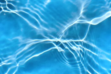 Blue water with ripples on the surface. Defocus blurred transparent blue colored clear calm water surface texture with splashes and bubbles. Water waves with shining pattern texture background.