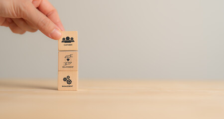 CRM, Customer relationship management concept. Customer satisfaction, retention strategies. CRM or customer loyalty program banner. Wooden cube blocks with CRM symbols on minimal background.