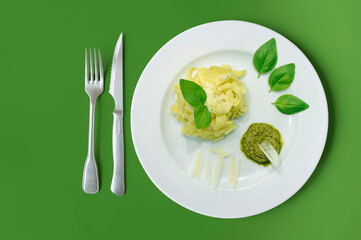 Pâtes au pesto et parmean dans une assiette sur fond vert