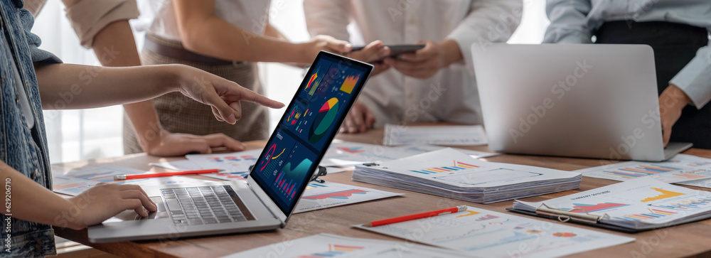 Poster Panorama shot analyst team utilizing BI Fintech to analyze financial report with laptop. Businesspeople analyzing BI power dashboard displayed on laptop screen for business insight. Scrutinize