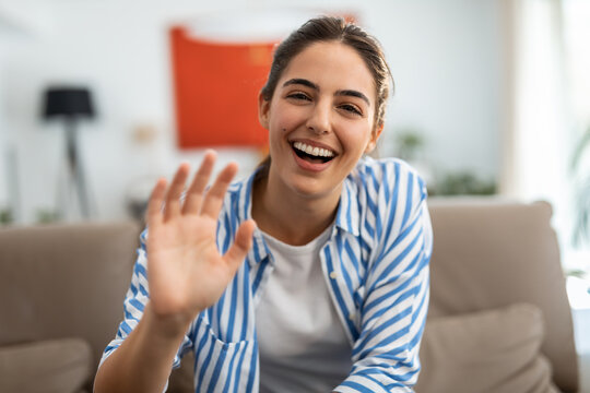 Beautiful happy woman doing video call while sitting on a couch in living room at home