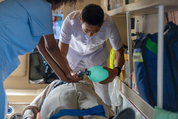 Two rescuers helping a patient to breath properly in am ambulance van. Paramedics work together to...