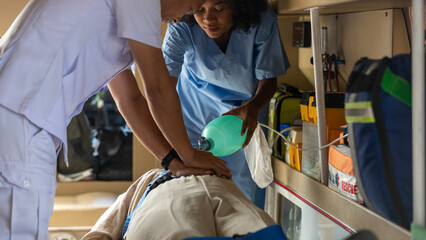 Two rescuers helping a patient to breath properly in am ambulance van. Paramedics work together to...