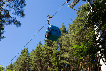 Bottom view of gondola lift, modern cable car and tourist attraction in forested mountains